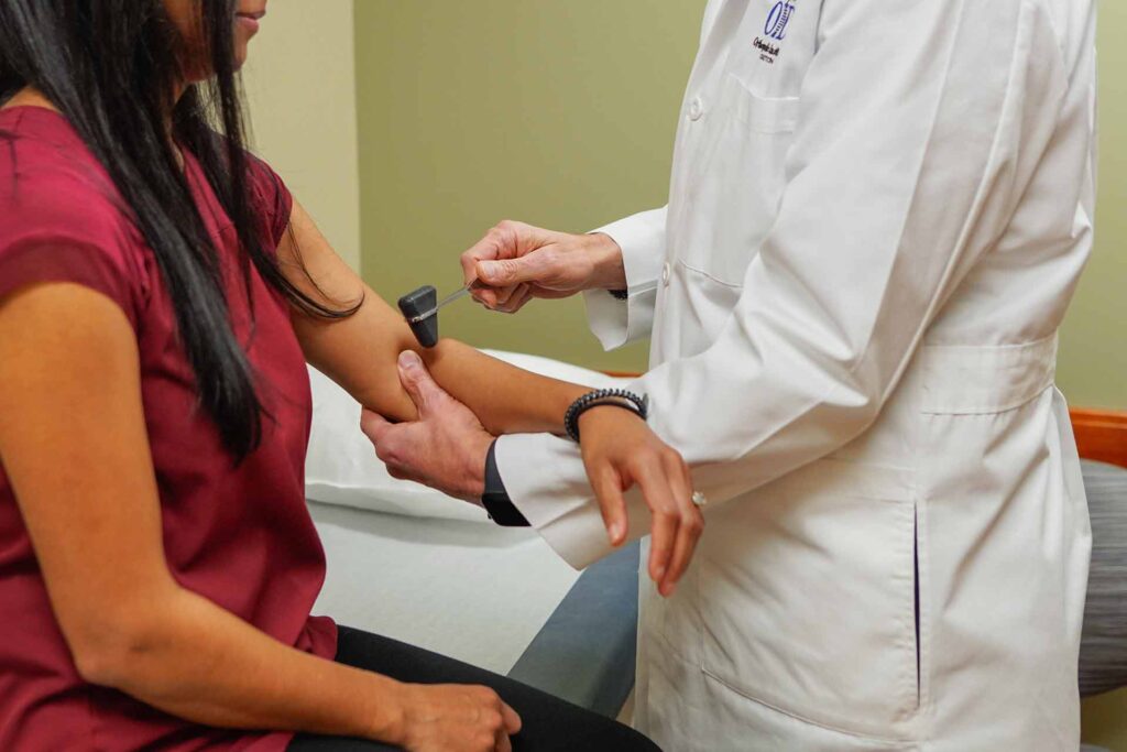 A close of a doctor examining a female patients elbow