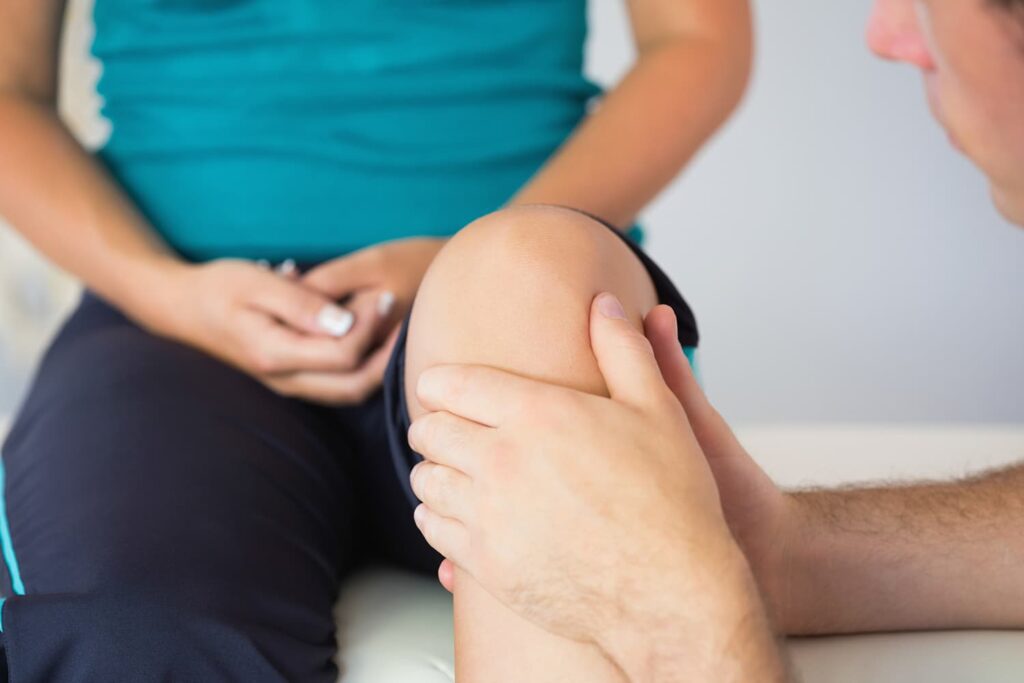 A close up of a doctor examining a patients knee