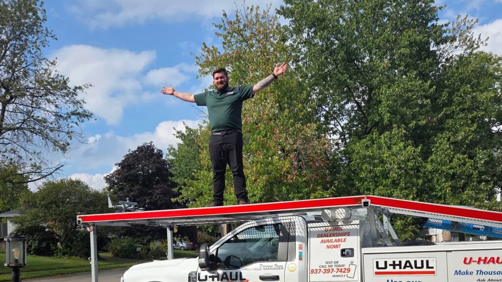 A man outside standing on top of a U Haul