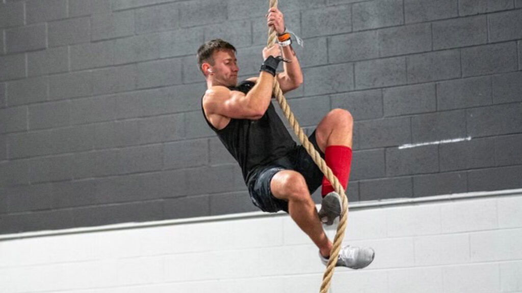 A man in workout gear climbing a rope